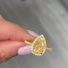 a woman's hand holding a yellow diamond ring