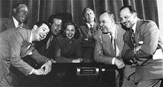 a group of men and women posing for a photo in front of a radio