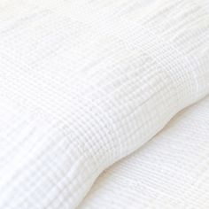 a close up view of the textured white linens on a bedding set