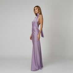 A captivating blend of elegance and allure, our Lylia Open Back Halter Dress exudes undeniable charm. Tailored with a flattering bias cut from lavender double silk satin, it drapes gracefully over the silhouette. The halter neckline delicately frames the shoulders, while the revealing back adds a note of sensuality. For a playful and feminine look, you can transform the silk tie neck into a chic bow, or you can let it drape loosely, adding a touch of laid-back sophistication to your ensemble.  W Purple Silk Dresses, Lavender Formal Dress Long, Satin Lavender Bridesmaid Dresses, Purple Satin Bridesmaid Dresses, Satin Purple Dress, Halter Neck Satin Dress, Satin Open Back Dress, Elegant Purple Dress, Lavender Satin Dress