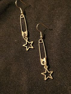 Safety pins on earring hooks, accented with open (hollow) star charms, set of 2 earrings, each measures about 2.5 inches.  Silver tone.  Handmade, unisex jewelry.  Ready to ship. To continue shopping: http://www.rrrobinnn.etsy.com Cheap Pendant Necklaces For Streetwear, Cheap Trendy Dangle Charms, Luxury Modern Metal Plug Earrings, Luxury Hammered Fine Jewelry Necklaces, Heart Safety Pin Earrings Target, Cheap Metal Earrings For Streetwear, Cheap Silver Hoop Beaded Earrings, Cheap Themed Pierced Jewelry, Cheap Adjustable Jewelry For School