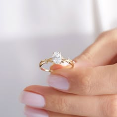 a woman's hand holding an engagement ring with a diamond on the middle finger