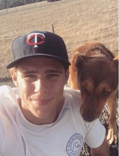 a man and his dog posing for a photo in front of a fenced field