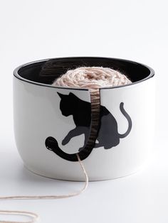 a white bowl with a black cat on it and a string in front of it