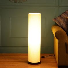 a floor lamp sitting on top of a hard wood floor next to a couch in a living room