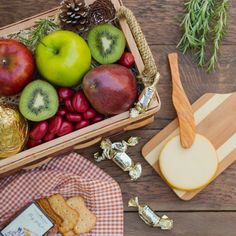 a basket filled with apples, kiwis and crackers on top of a wooden table