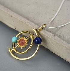 Description & Details The design concept of the planet's orbit also implies that time is constantly passing. • Material: Solid 925 Sterling Silver ∙ Sunstone ∙ Lapis Lazuli ∙ Turquoise• Finish: Hypoallergenic ∙ Gold Plating• Dimensions: 20 mm diameter pendant, no chain• All our work is custom made by hand with love Celestial Sun And Moon Design Necklace As Gift, Celestial Sun And Moon Sterling Silver Necklace, Celestial Necklaces With Sun And Moon Design For Gift, Celestial Sun And Moon Jewelry, Celestial Jewelry With Sun And Moon Designs, Celestial Metal Pendant Jewelry, Handmade Silver Cosmic Jewelry, Handmade Brass Celestial Necklace, Celestial Sun Design Round Jewelry