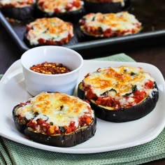 two stuffed eggplant halves on a white plate with a cup of coffee in the background