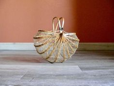 a gold purse sitting on top of a hard wood floor next to a red wall