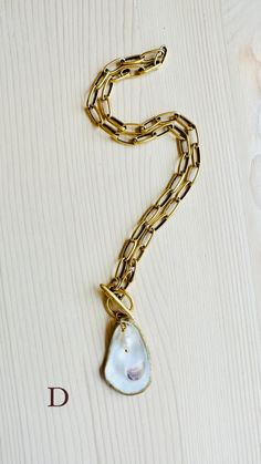 A truly One-of-a-Kind statement piece. Hand painted gold leaf natural oyster shell pendants with gorgeous freshwater pearls, on high quality 12K Gold over brass chain with toggle front closures. Each shell has been harvested in our Charleston, SC rivers and are carefully hand finished to create its one-of-a-kind appearance. No two shells are alike. Each oyster shell has its own story behind its journey to the shore. The size, shape and colors in each one will vary and that is what makes each she Unique Gold Shell Necklaces, Gold Shell Necklace With Baroque Pearl Pendant, Gold Shell Necklace Made Of Mother Of Pearl, Gold Shell Jewelry With Adjustable Chain, Artisan Gold Jewelry With Pearl Charm, Gold Shell-shaped Mother Of Pearl Necklace, Gold Shell-shaped Necklace With Pearl Chain, Gold Shell Jewelry With Pearl Chain, Gold Shell Pearl Chain Jewelry