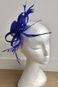 A stunning rich royal blue coloured Fascinator crafted out of light Sinamay fabric. A striking triple flower and loop design, complemented by delicate feather detailing in the same shade makes this Fascinator hat a beautiful addition to any outfit. This piece sits firmly on the head with a co-ordinating satin covered comb. This design can also be created on a headband or a clip if you would prefer, please just advise at checkout. Fascinator measures 19cm x 12cm. Comb measures 9cm x 4.5cm. Our timeless pieces are perfect for any special occasion from Weddings to The Kentucky Derby and Summer Garden Parties! We offer ready to wear pieces in a variety of styles and colour! However if you want to make your piece unique, we can customise any piece with additional feathers and make it your own! Luxury Blue Fascinator For Royal Ascot, Blue Headband For Party, Elegant Blue Costume Hat For Evening, Blue Headband For Royal Ascot, Blue Evening Hat For Royal Ascot, Blue Fitted Headband For Kentucky Derby, Blue Adjustable Headband Fascinator, Elegant Blue Headpiece For Royal Ascot, Adjustable Blue Headband Fascinator