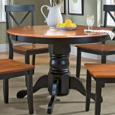 a dining room table with four chairs and a bowl of fruit on top of it