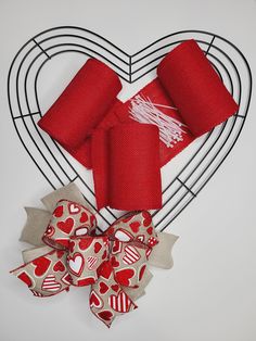 two red and white hearts on a wire heart with bows attached to it, sitting next to each other