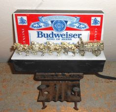 an old budweiser beer sign is sitting on top of a piece of metal