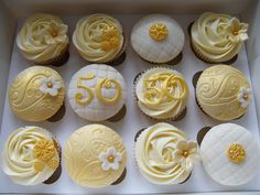 twelve decorated cupcakes in a box with white frosting and yellow icing