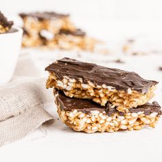 two pieces of chocolate covered granola bars next to a white bowl