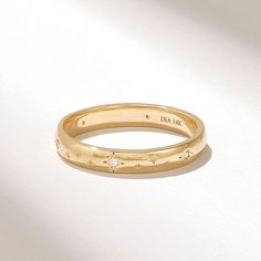 a close up of a gold ring on a white surface with the word daa sak written in cursive writing