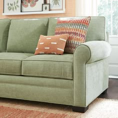 a green couch with pillows on it in a living room