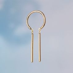 a pair of gold - plated silver earrings hanging from a hook on a blue background