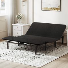 a black bed frame sitting on top of a rug in a living room next to a window