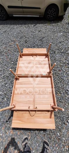 a person standing next to a wooden bed frame on top of gravel with their feet in the air