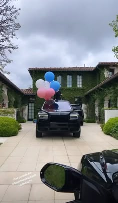 a car parked in front of a house with balloons attached to the top of it