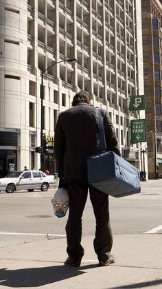 a man is walking down the street with his suitcases in hand and bags on his back