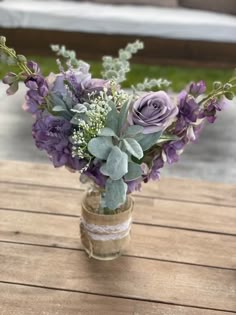 a vase filled with purple flowers on top of a wooden table