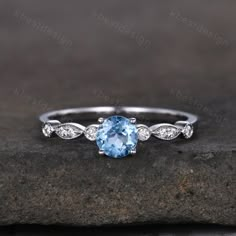 an oval blue topazte and diamond ring on a rock with white gold accents