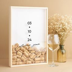 a wine glass and corks are next to a photo frame with the date on it