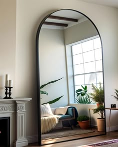 an arched mirror in the corner of a living room with a couch and potted plants