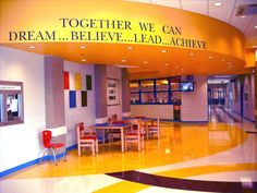 the inside of a school building with tables and chairs in front of a sign that says, together we can dream believe lead achieve