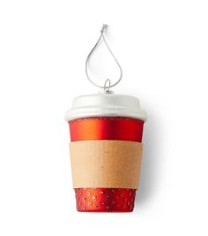 a red and white coffee cup hanging from a string on a wall with a chain attached to it