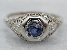 The height of Art Deco craftsmanship, this sapphire, and 18 karat white gold ring is set with bright diamonds, glittering and sparkling. Along with the detailed engraving work on all sides of the ring and the band, they are the perfect accent for the round cut and dark blue sapphire in the center. This gem has flashes of intense, saturated blue; a gorgeous combination with the white gold and diamonds. This can be worn as an engagement ring, an everyday ring, or just for special occasions!Metal: White Sapphire Solitaire Ring, Seed Pearl Ring, Saturated Blue, Diamond Accent Ring, Sapphire Solitaire, White Gold Sapphire, Everyday Ring, Gold Art Deco, Diamond Anniversary Rings