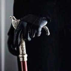 a person wearing black gloves and holding an ornate handle