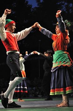 two people dancing on stage with their arms in the air