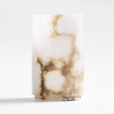 a white and brown marble vase sitting on top of a table next to a wall