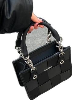 a person holding a black purse with chains attached to it's handles and the bottom section