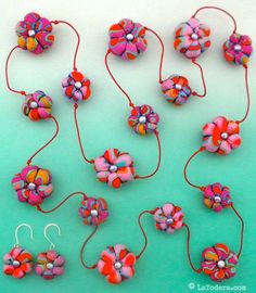 several colorful flowers are attached to earwires on a blue background with two pairs of earrings