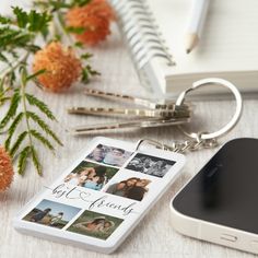 a cell phone is sitting next to some flowers and a keychain that has photos on it