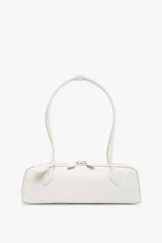 a white handbag is shown against a white background, with the handle on it