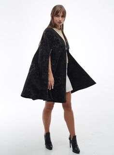 Wool Cape Women Loose Fit Cozy Stylish Oversized Coat  Poncho Cape - a women's mid-season coat crafted from a semi-woolen coat fabric in a loose, cape-like silhouette. The front panels feature slits for the arms, elegantly trimmed with faux leather. The garment is unlined. The cape is adorned with a patch and a leather closure with a loop and button. The fastening is along the edge with a loop closure and button. Back length: 81-84 cm. Fabric Composition: 80% Wool, 20% Polyester Black Oversized Cape For Spring, Oversized Black Cape For Spring, Oversized Cape Outerwear For Spring, Oversized Chic Cape For Spring, Chic Oversized Cape For Spring, Oversized Wool Cape Coat For Fall, Oversized Winter Cape For Work, Oversized Wool Sweater Coat For Spring, Chic Spring Cape Outerwear