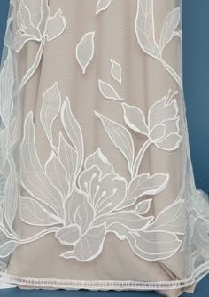 the back of a dress with white flowers and leaves on it, against a blue background