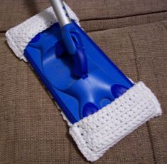 a blue and white mop laying on top of a couch next to a cleaning cloth