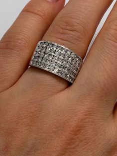 a woman's hand with a silver ring on top of her finger and two diamonds in the middle