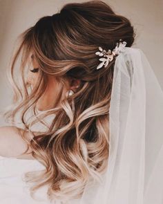 a woman with long hair wearing a veil and flowers in her hair is seen from the side