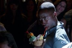 a young man eating an ice cream sundae in front of a group of people