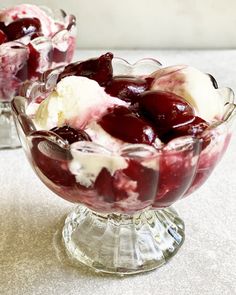 two glasses filled with ice cream and cherries on top of a table next to each other