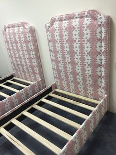 two pink and white beds with wooden slats on top of each bed headboard