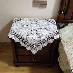 a white crocheted table cloth on a wooden nightstand